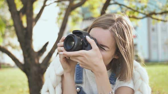 The Girl Takes Pictures of Nature in the Park in the Summer