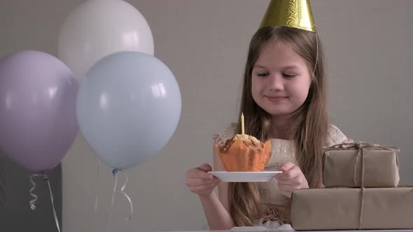 Cute Little Child Girl in Party Hat Sitting Surrounded By Air Balloons and Gifts Going to Celebrate