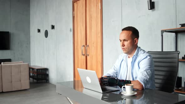 Serious man freelancer with high temple and artificial limb types on laptop