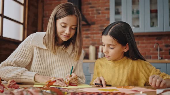 Young Mother Circling Orange Leaf Laying on White Sheet of Paper with Pencil