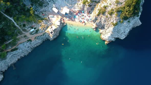 Tourists Swimming At Turquoise Sea Water On Klancac Beach In Brsec, Croatia. - aerial