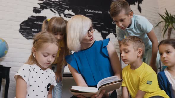 Children Sit on Floor on the Pillows as Teacher Reads to Them Interesting Book