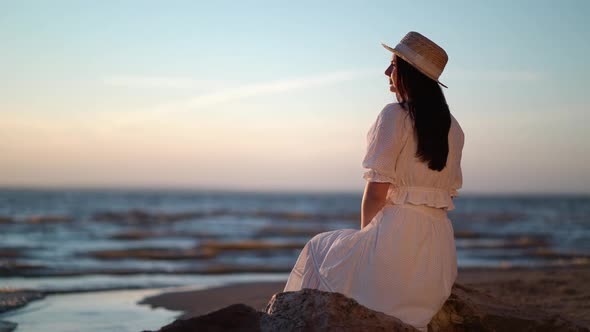 Woman in Dress Relaxing Sitting on a Big Stone in Sea