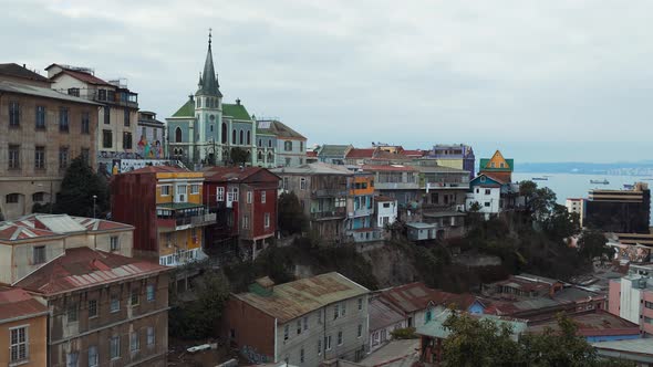 Pan right of colorful hillside houses and Lutheran church from Cerro Alegre in Valparaiso city, sea