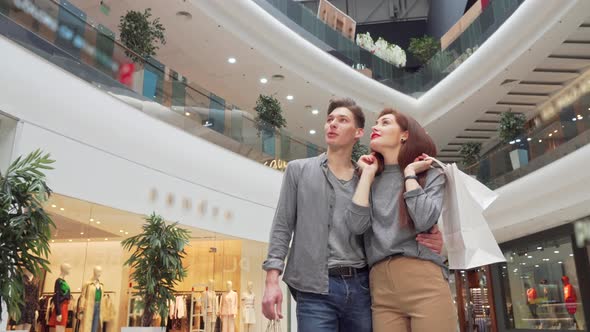 Low Angle Shot of a Young Couple Looking Around at the Shopping Mall