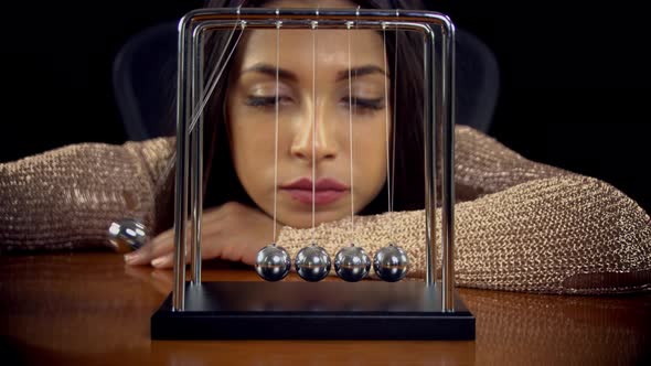 Woman Playing With A Newton's Cradle