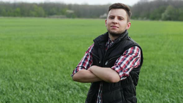 Close-up Portrait of Successful Farmer Man Looking To Camera in the Green Wheat Field