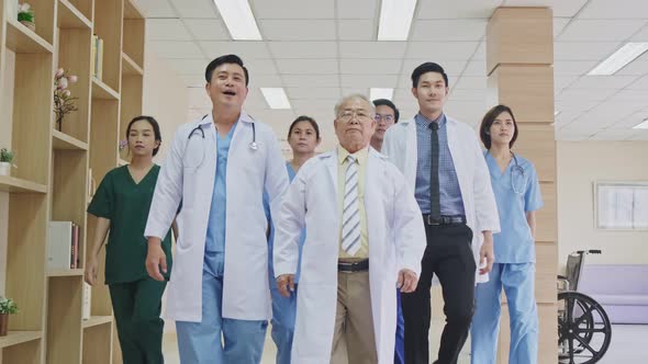 Group of Asian team of doctors, nurses and assistants walking through the hallway of the hospital.