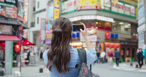 Backpacker woman visit Tokyo city, take photo on cellphone