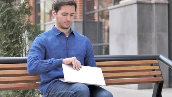 Young Man Coming and Sitting on Bench to Use Laptop