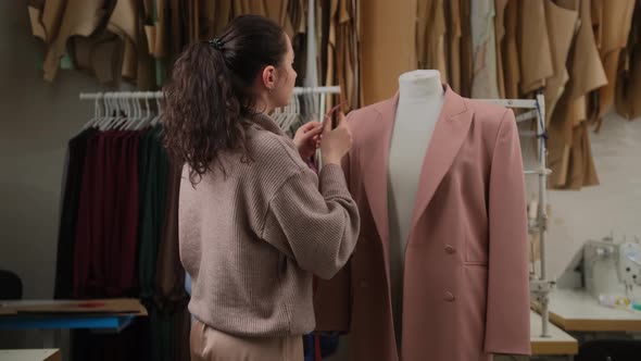 seamstress is measuring clothing on tailoring dummy with measure-tape. Woman is concentrated