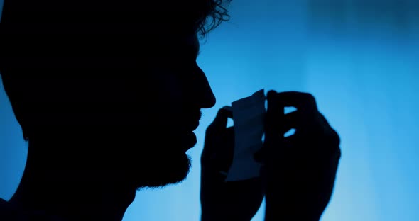 Silhouette of a person puts on a mask.