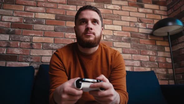 Closeup Front View of Relaxed Young Man Holding Controllers and Playing Video Games on Console