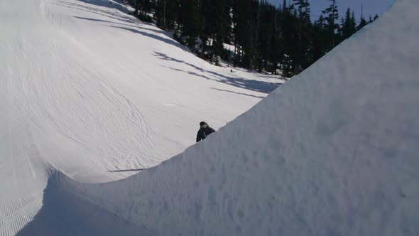 A young man snowboarder going off jumps in a terrain park.