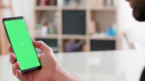 Man Holds in His Right Hand a Smartphone with Gren Screen on