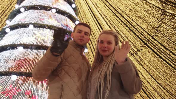 Young Loving Couple at Christmas Celebrating Outdoors  Waving To the Camera