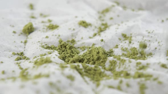 Powdered green matcha tea falls onto a white paper napkin