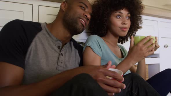 Happy mixed race couple drinking coffee in their kitchen