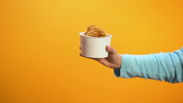 Woman Taking Offered Crunchy Chicken Wing on Yellow Background, Unhealthy Snack