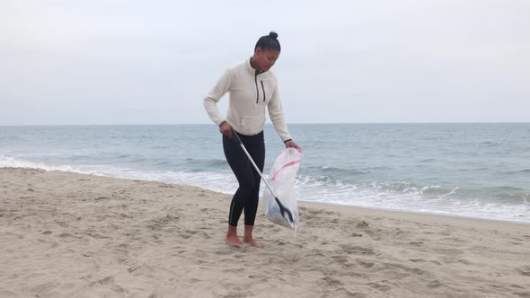 Woman picking up litter from the bech.