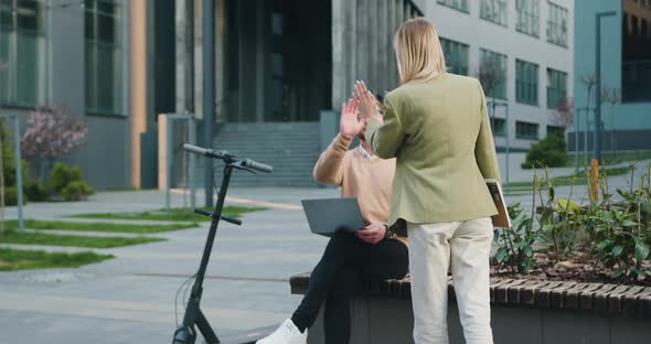 Man and Woman Sitting on Bench by Modern Office Building in Smart Casual Business Style