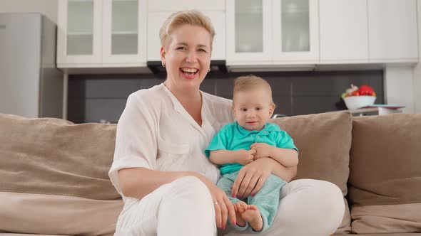 Mother Smiling and Looking at Camera While Playing with Son