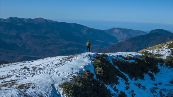 A man walks runs on top of snow covered mountains