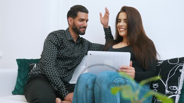 White Woman with Long Dark Hair Working on Laptop Looking at Her Partner Watching Her and Smiling