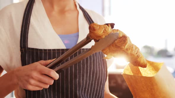 Waitress packing croissants in paper bag at caf������������