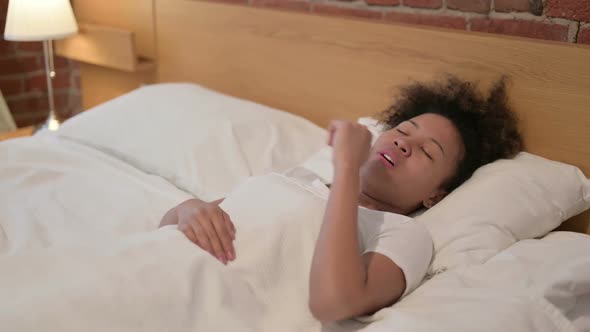 African Woman Coughing While Sitting in Bed