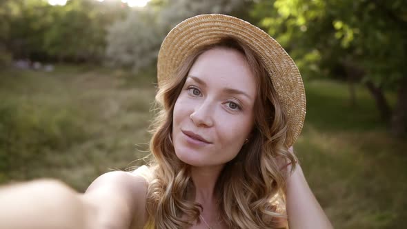 Young Blonde Woman Making Selfie in Straw Hat Funny Face Posing at Countryside at Summer Day