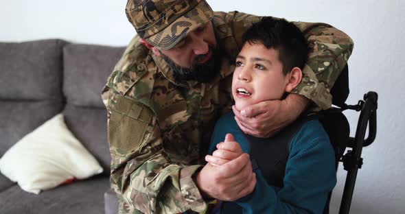 Happy veteran soldier man hugging his son in wheelchair after returning from military service