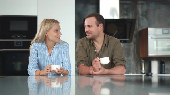 Cute Young Couple Drinking Coffee in Kitchen and Chatting During Breakfast