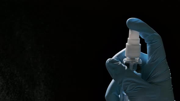 A Hand in a Blue Protective Glove Sprays an Antiseptic on a Black Background. Spray Disinfection