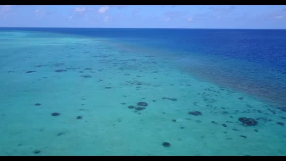 Aerial flying over sky of tranquil lagoon beach break by blue green ocean and white sand background 