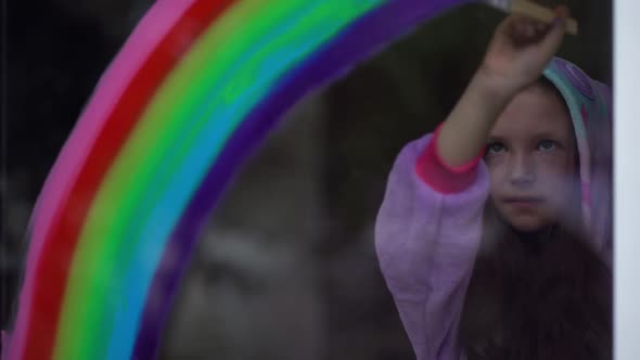 Stay Home, Flash Mob Chase the Rainbow. Girl in Pajamas Draws the Rainbow on the Window at Home