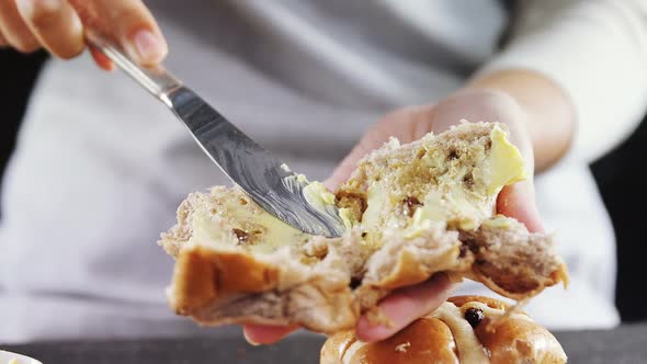 Woman applying butter over multigrain bun