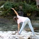 woman is practicing yoga in Warrior Pose (Virabhadrasana) pose at mountain lake - VideoHive Item for Sale