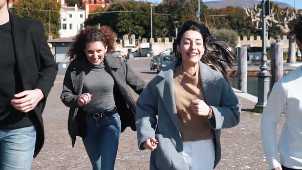 Slow motion shot of smiling friends running at seafront