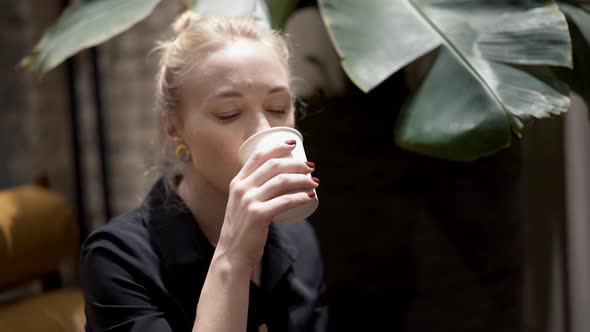 Handheld Close Up of Blonde Woman with Hair in a Bun Drinking Wine