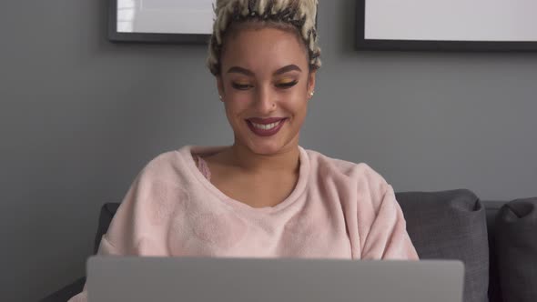 Young Business Woman Working on Laptop and Smiling on Sofa at Home