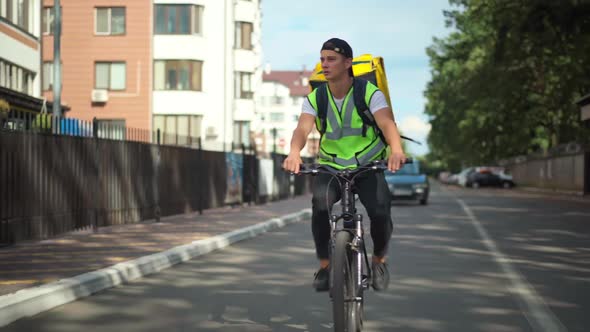 Concentrated Delivery Boy Searching Address Riding Bike in Residential Neighborhood Gesturing Thumb