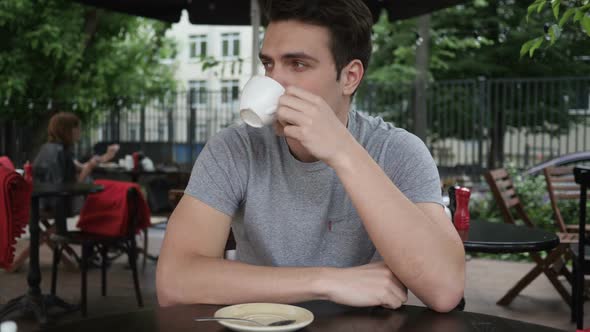 Young Man Drinking Coffee While Sitting in Cafe Terrace
