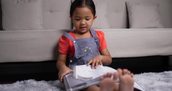 Asian girl sitting and practicing reading on the floor