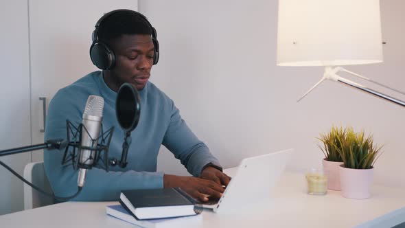 Man Wearing Headphones Taking an Online Class Using a Laptop and Microphone