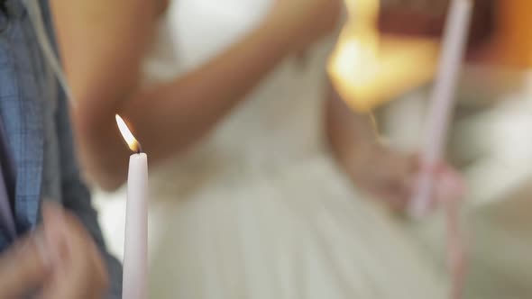 The Bride and the Groom Stand in Church, Holding Candles in Their Hands