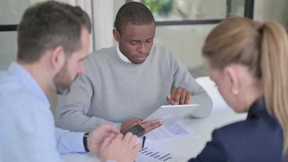 Male and Female Businessperson Using Tablet and Smartphone During Discussion