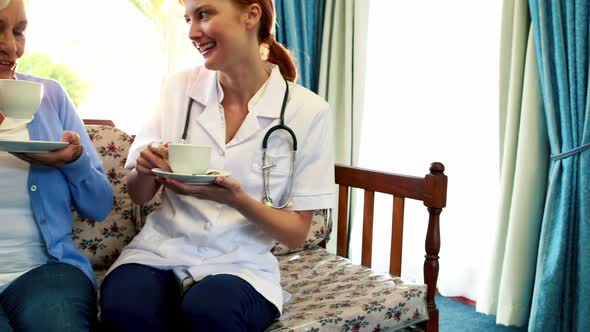 Nurse and senior patient drinking coffee together