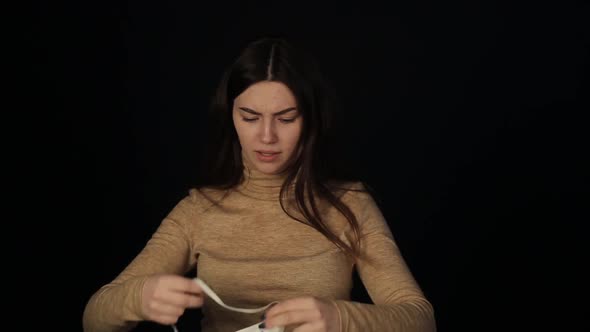 A Beautiful Young Caucasian Girl Wearing a Medical Mask Putting on a Medical Protective Mask. Girl