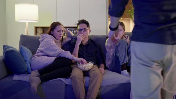 A Family of Three is Sitting on the Sofa and Watching TV